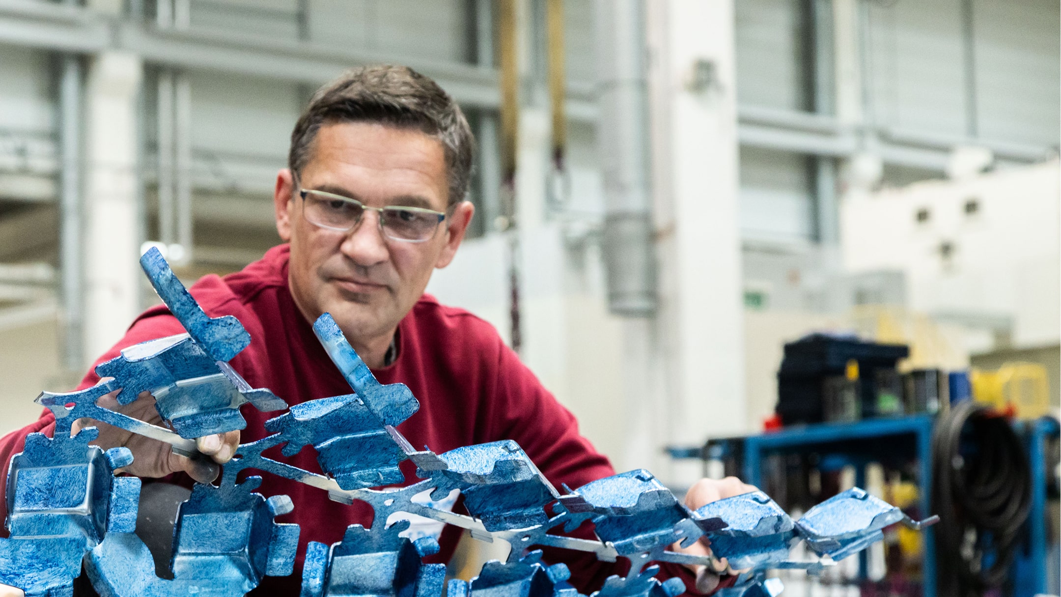 Ein Arbeiter überprüft ein Metallteil in einer Industriehalle.