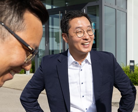 Führungskraft im Gespräch vor dem Bürogebäude von Sungwoo Hightech.