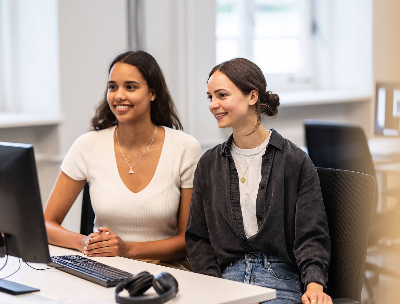 Zwei junge Praktikantinnen sitzen vor einem PC.