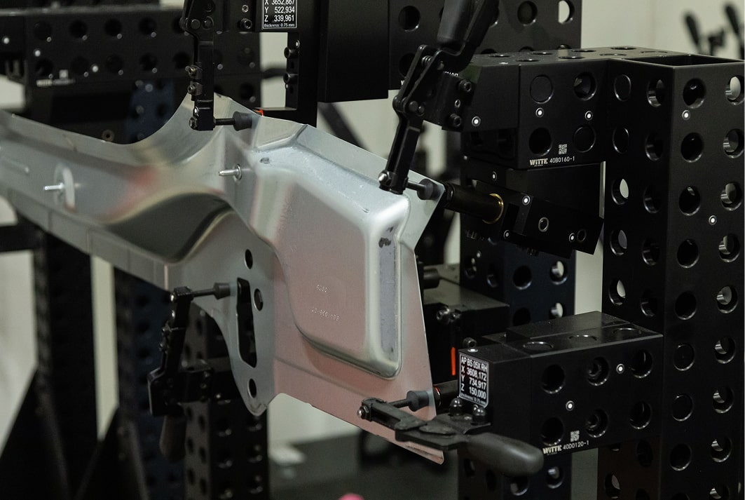 Metallbauteil in schwarzer Prüf- und Spannvorrichtung.